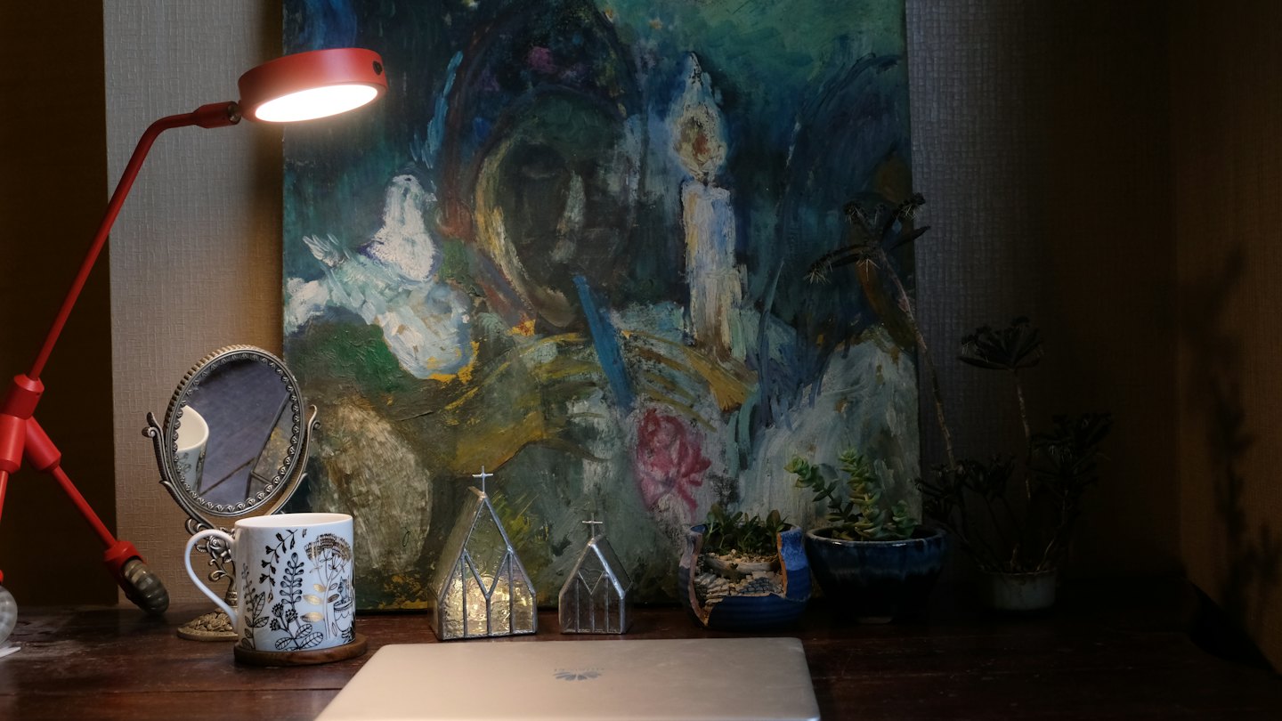 Laptop und Tasse auf einem rustikalen Holztisch mit einer roten Lampe.