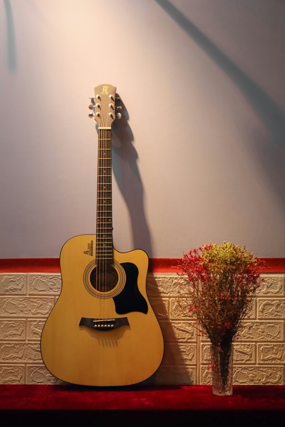 Akustikgitarre neben einer Vase mit Trockenblumen.